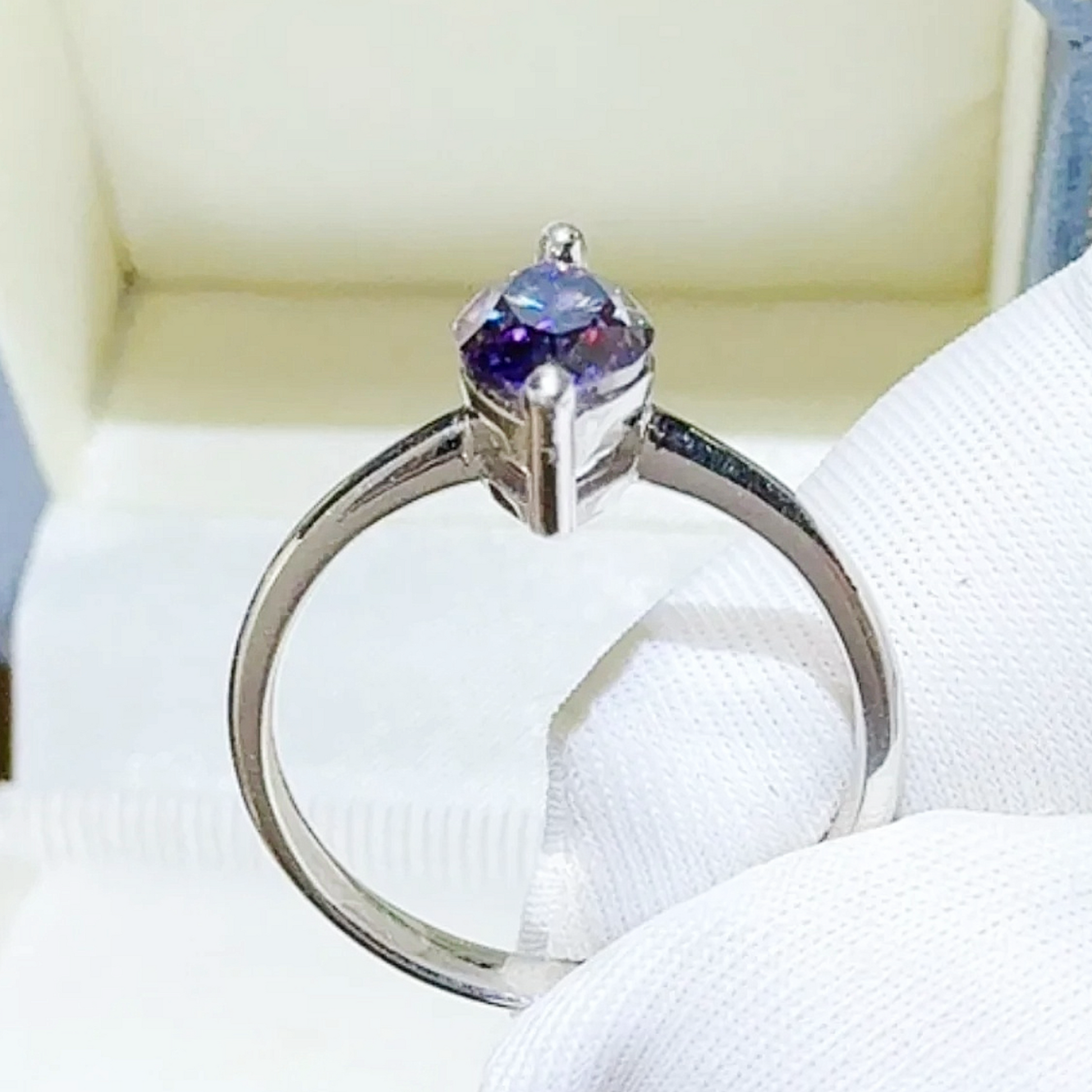 Silver ring with a purple gemstone on a white background
