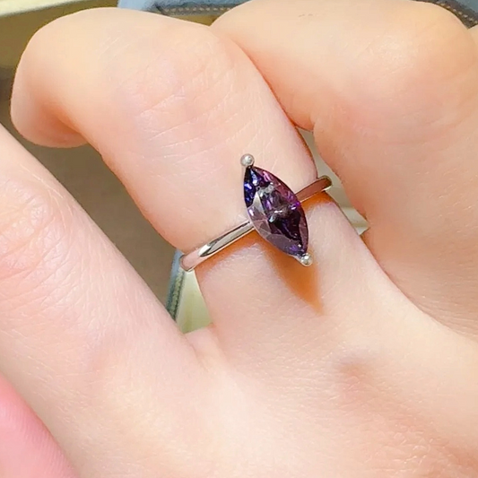 Silver ring with a purple gemstone on a finger