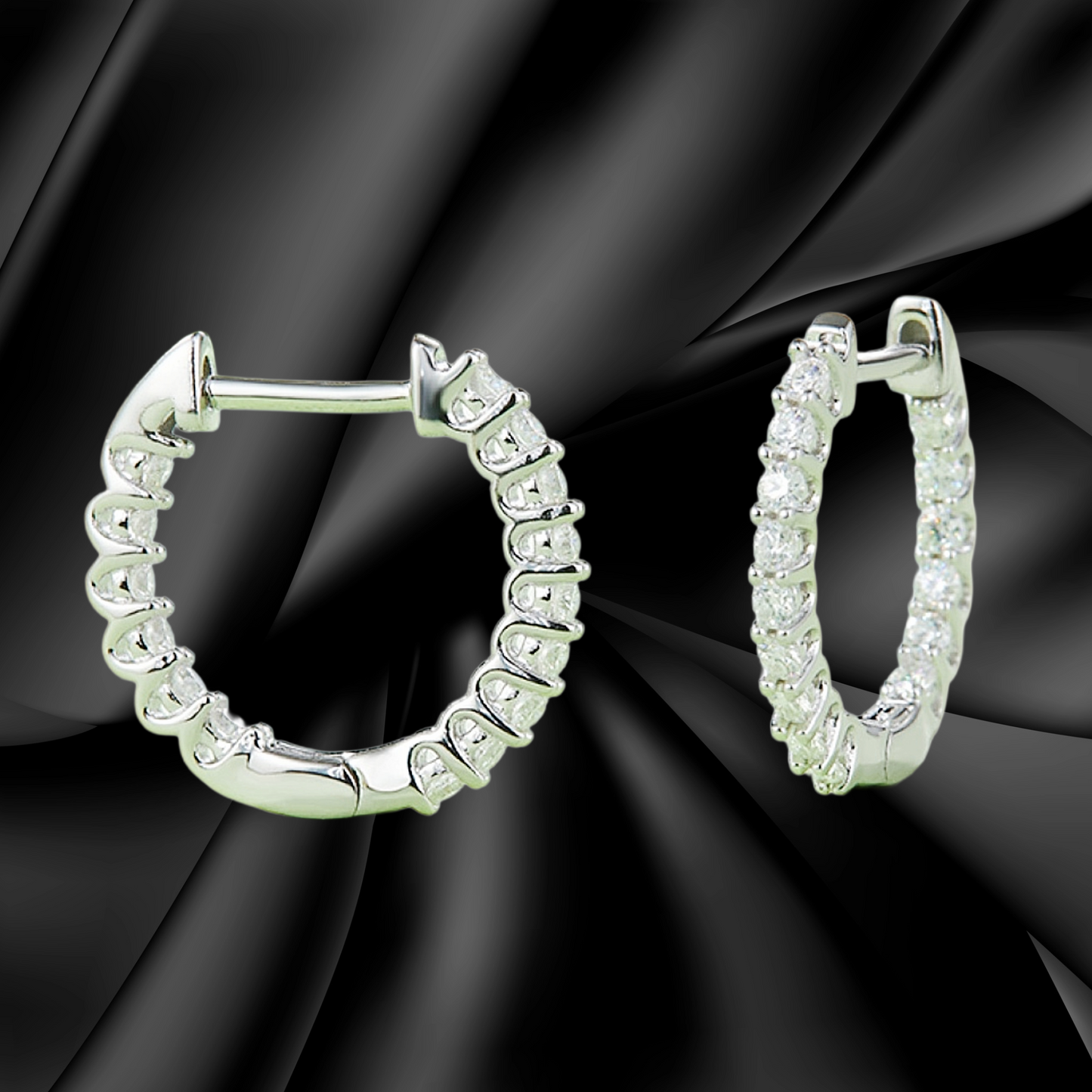Silver hoop earrings with clear gemstones on a black fabric background