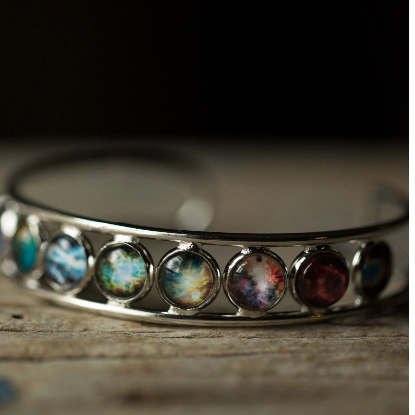 Silver bracelet with colorful gemstones on a wooden surface