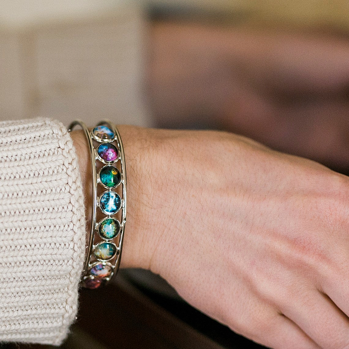 Close-up of a hand wearing a bracelet with colorful gemstones.