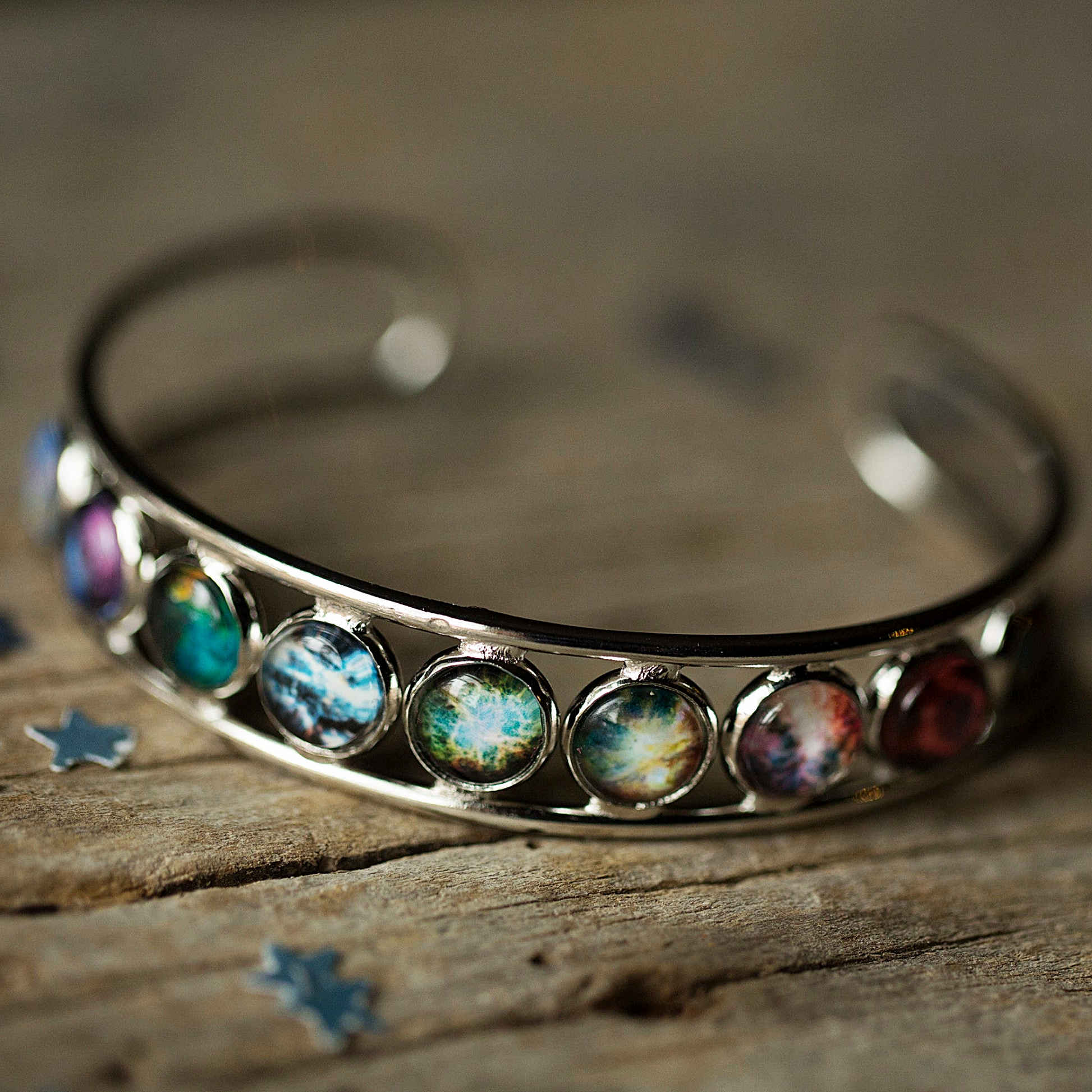Silver bracelet with colorful gemstones on a wooden surface