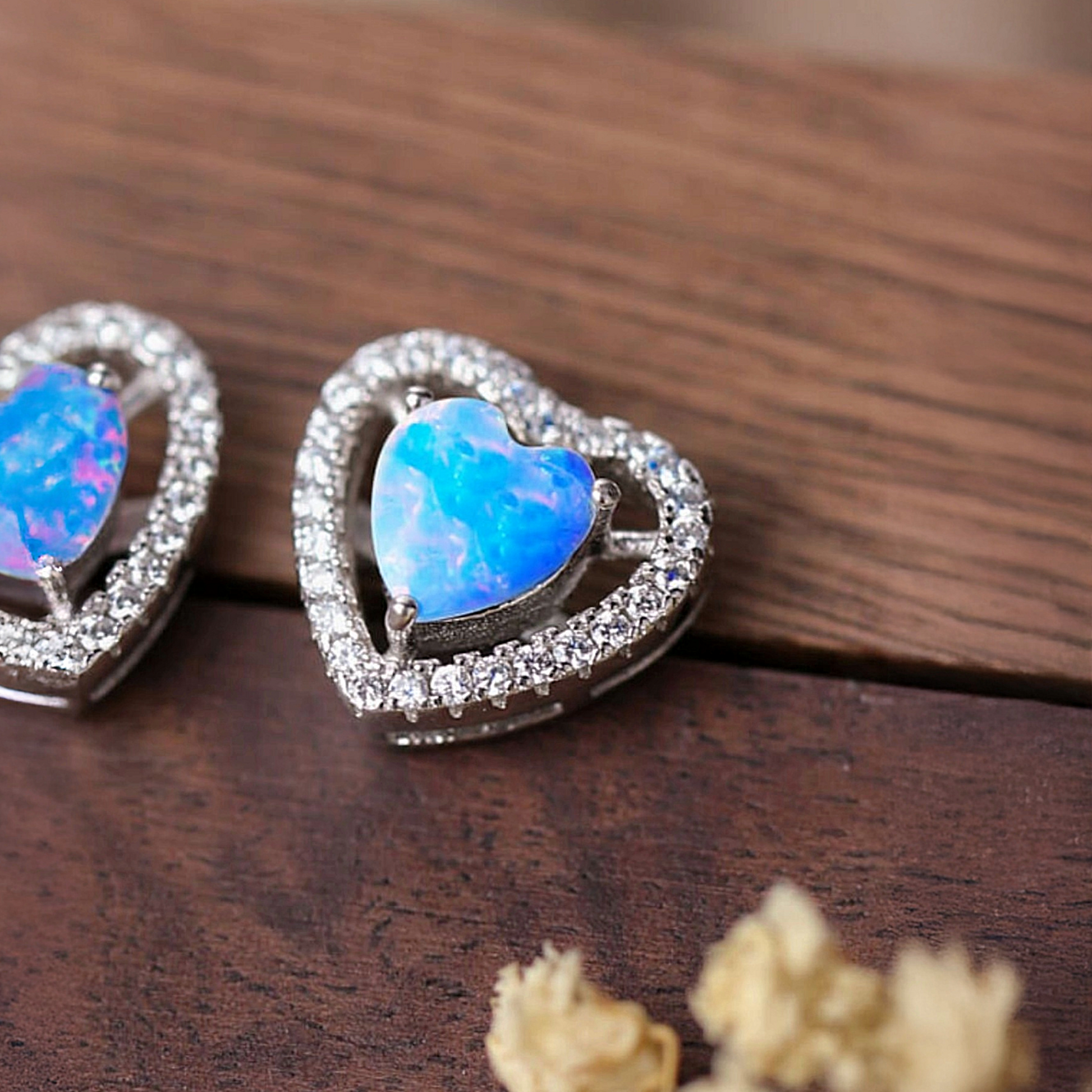 Heart-shaped earrings with blue gemstones on a wooden surface