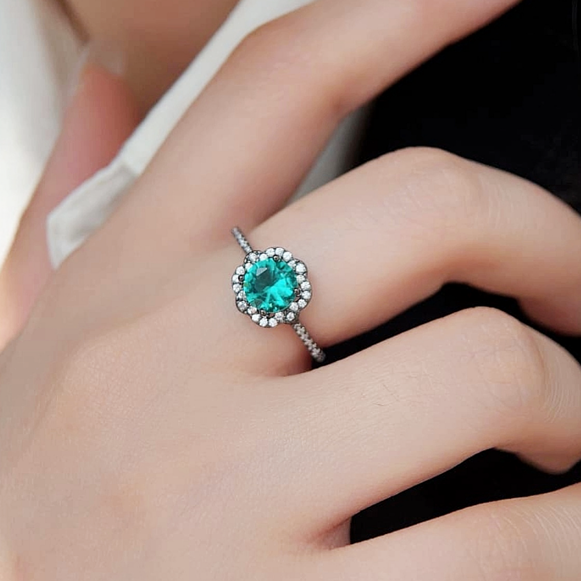 Model wearing Paraiba Noir™ ring on ring finger, vivid blue center stone and pavé halo visible