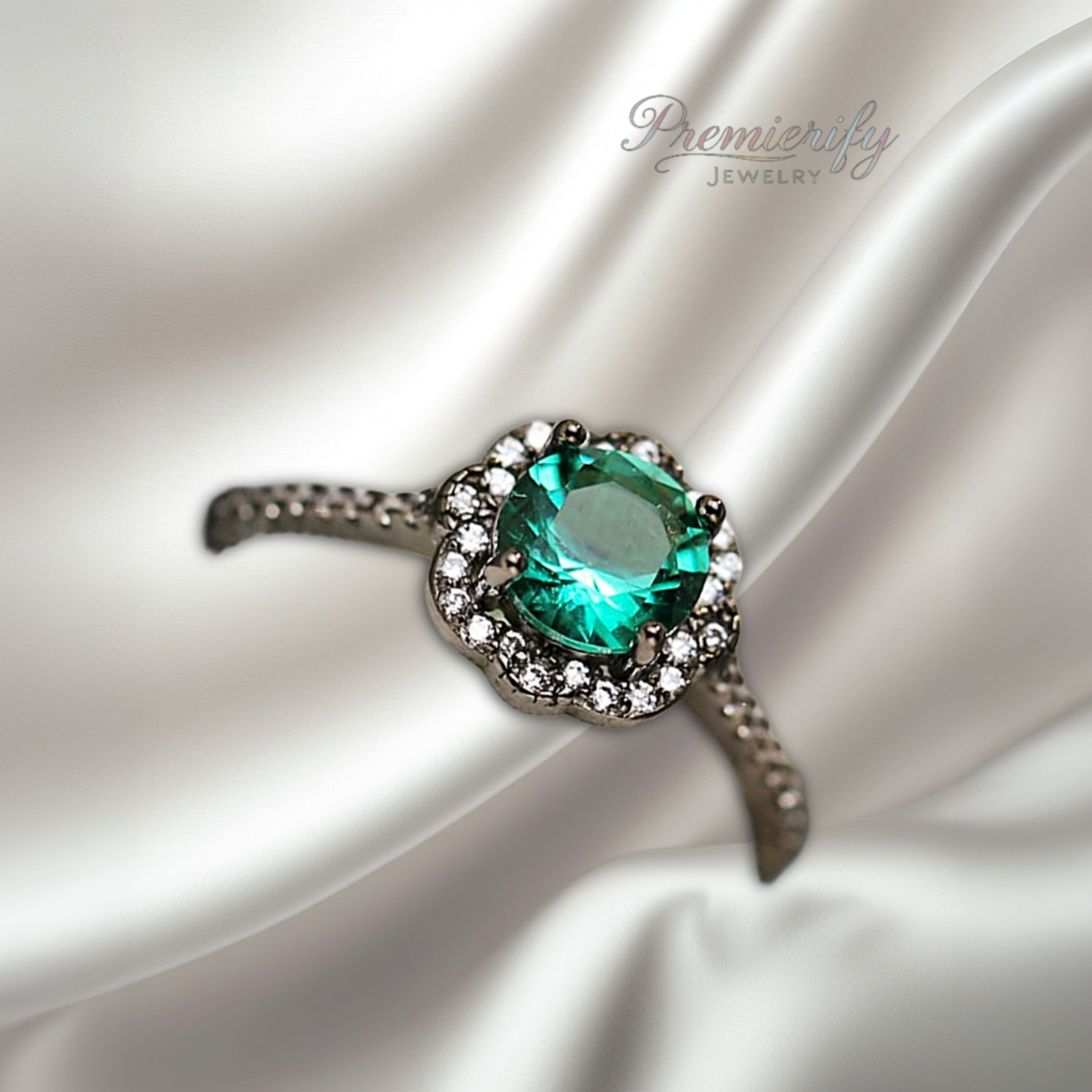 Ring with a green gemstone on a white satin background, featuring the brand 'PremierJewelry'.