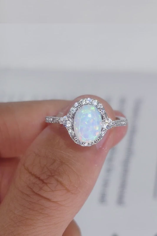 Short video of Iridesse™ oval opal halo ring in platinum-plated 925 silver, rotated in hand to show iridescent color play and sparkle