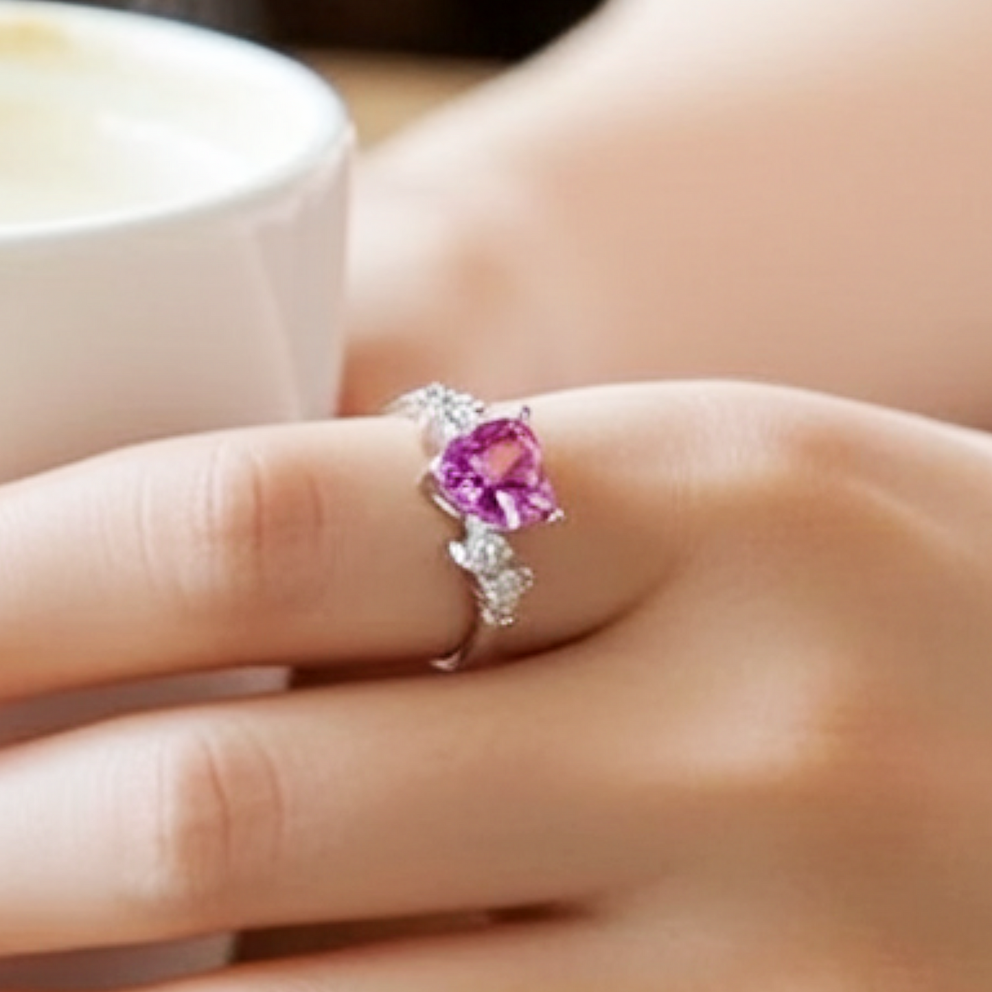 Close-up of a hand wearing a ring with a pink gemstone.