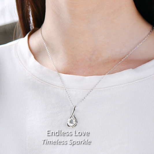 Person wearing silver Infinity necklace with gemstone center on white background.