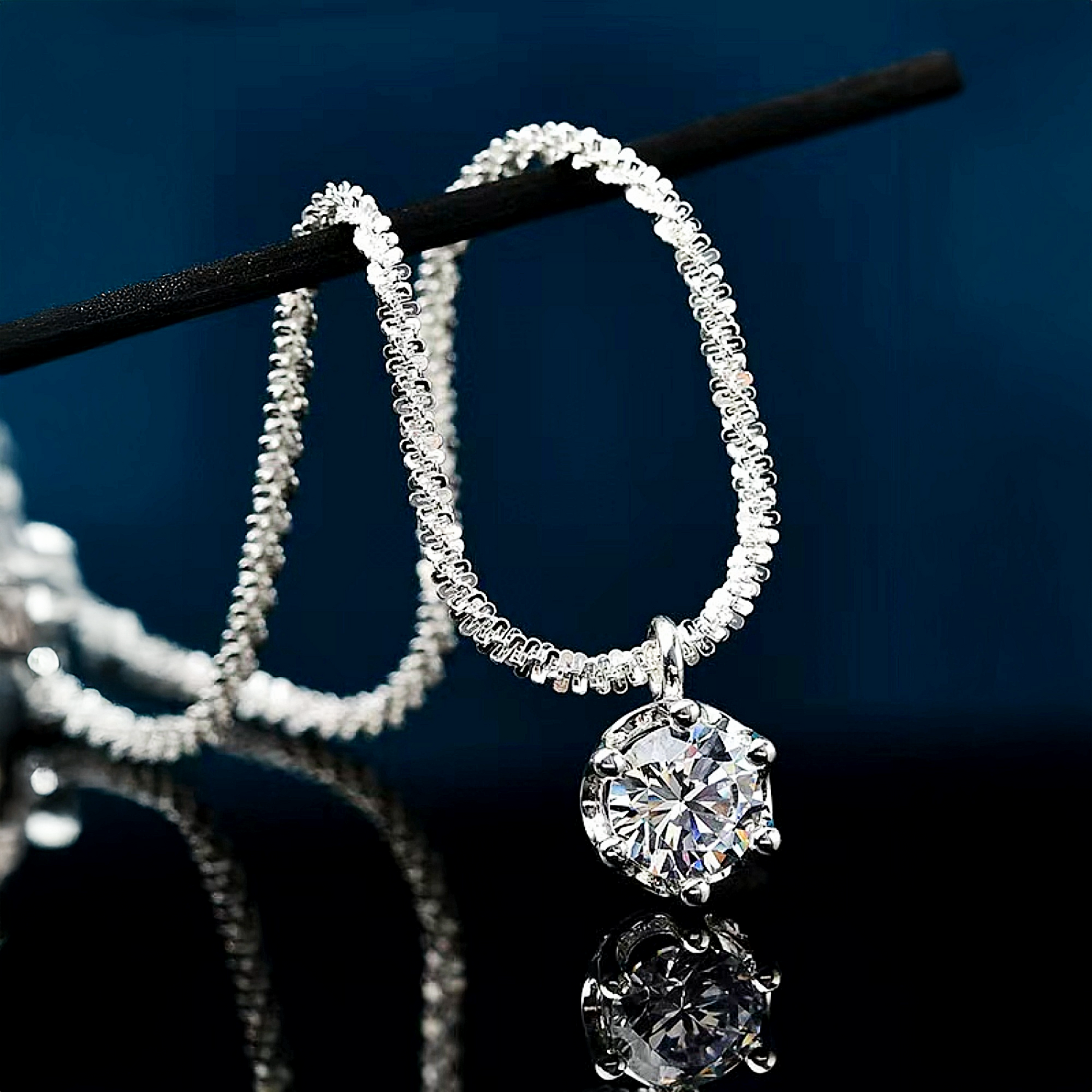 Silver hoop earrings with a central diamond on a dark background