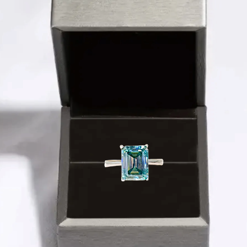 Ring with a green gemstone in a black jewelry box on a white background