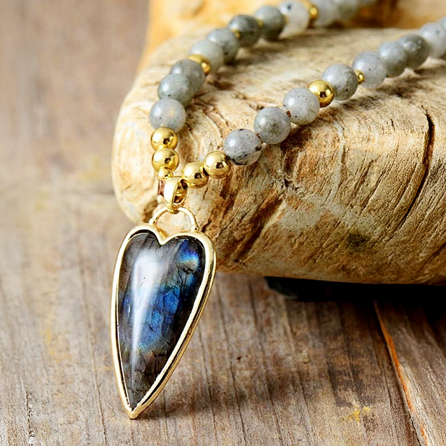 Necklace with a heart-shaped Labradorite pendant on a wooden surface
