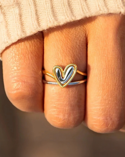 Heart-shaped ring on a finger with a blurred background
