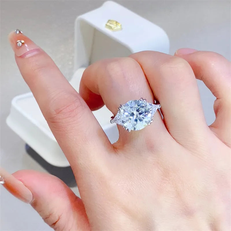  Large engagement ring on finger with white box in the background.